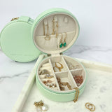 Mint green jewelry box with jewelry inside on a marble surface